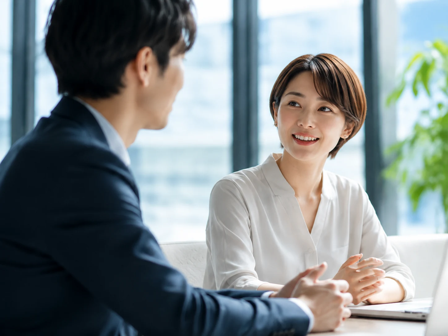 明るいオフィスで向き合って話す二人のイメージ
